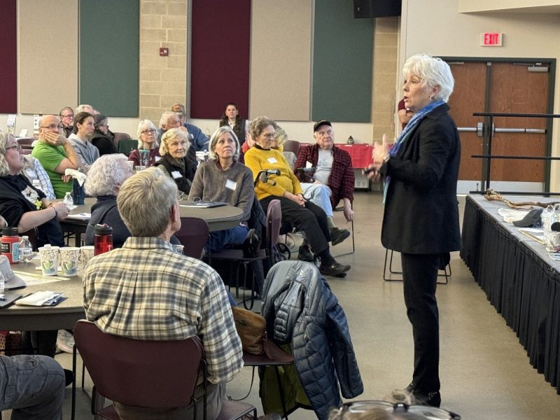 Woman in black jacket talks to a group of people