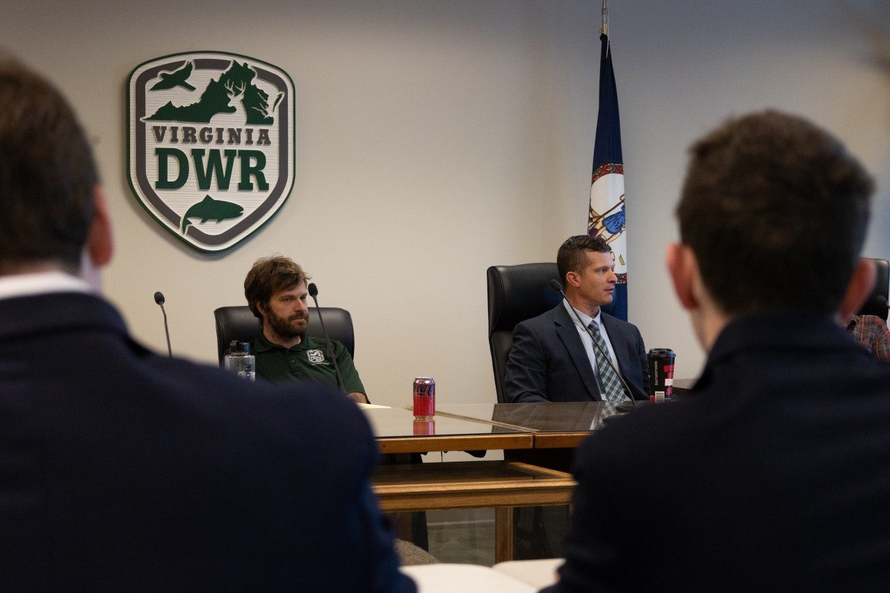 Two men in professional clothing talk with students.