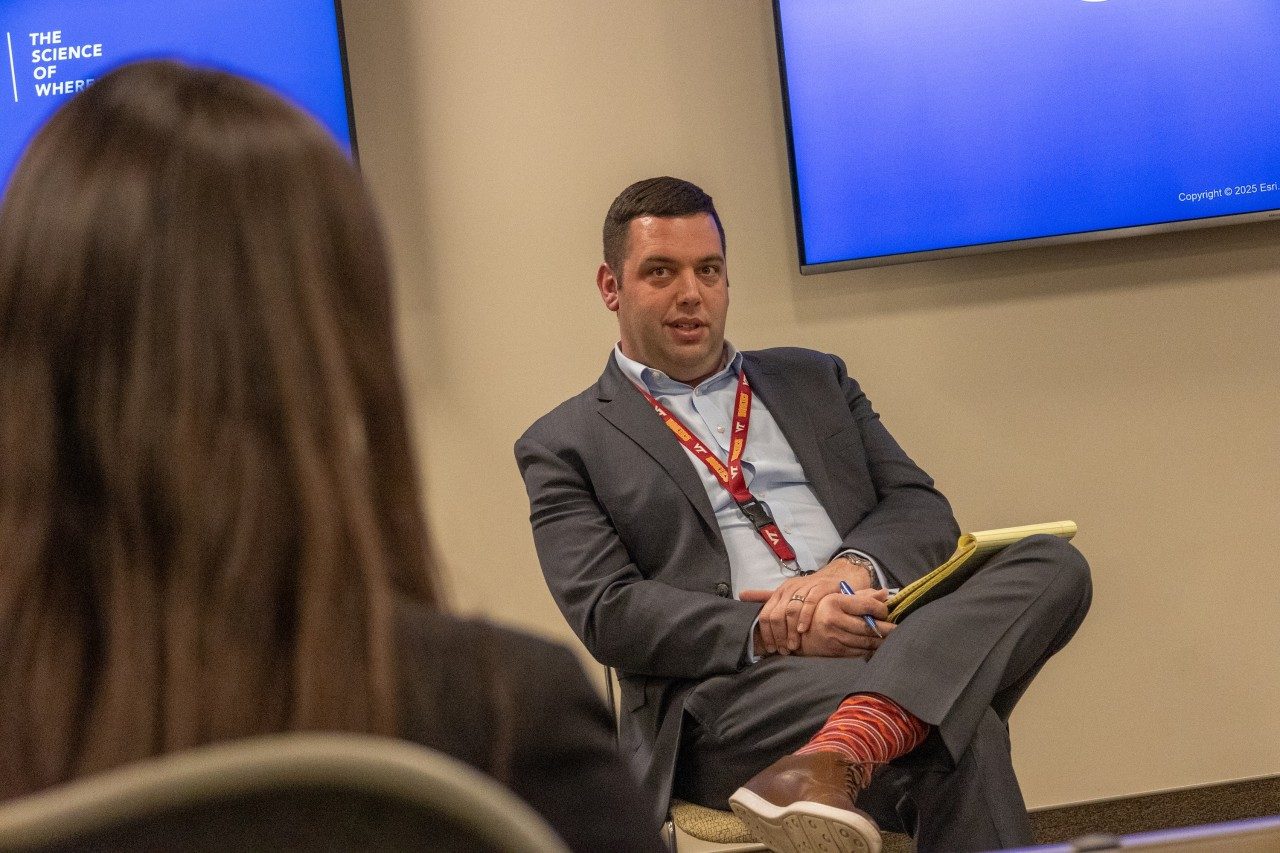 Man in suit with a maroon and orange lanyard.