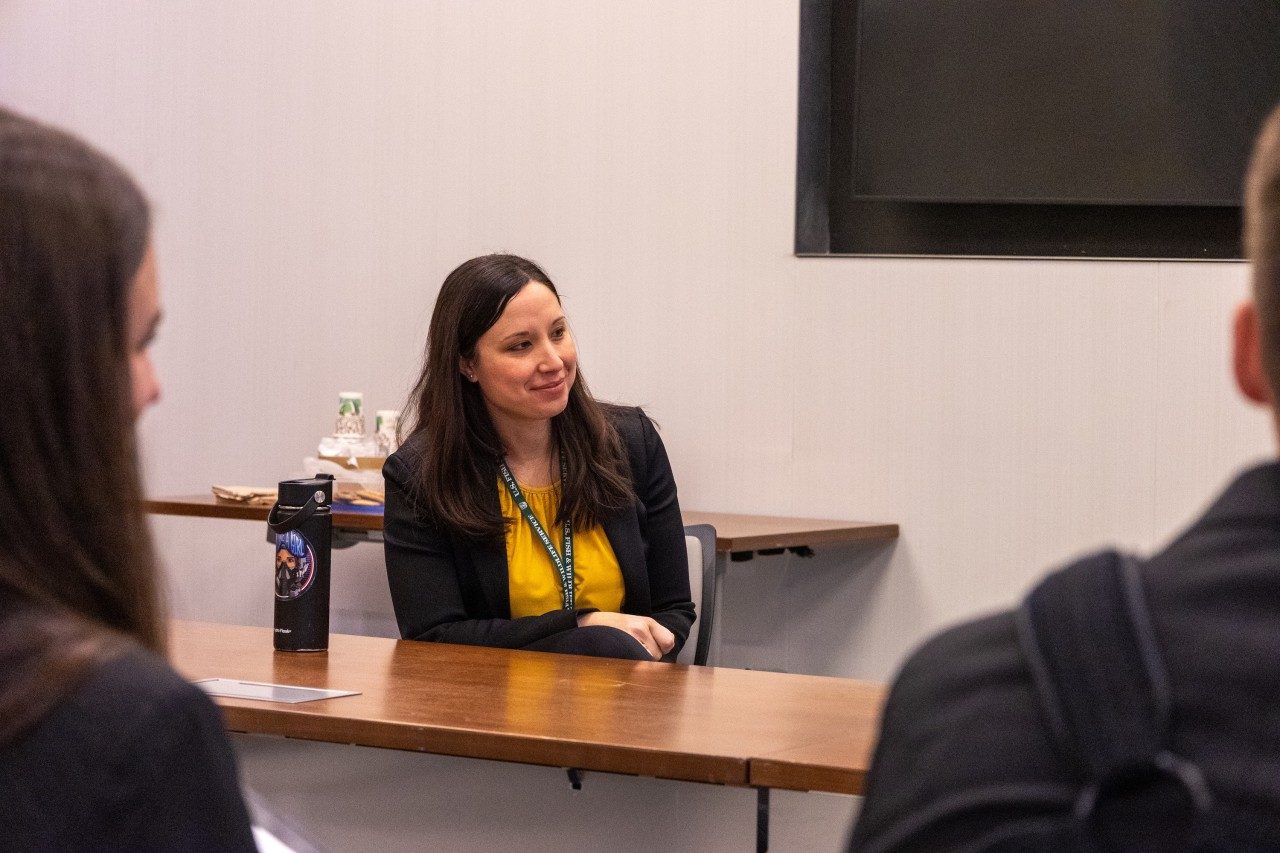 Woman in a dark blazer with a yellow top.