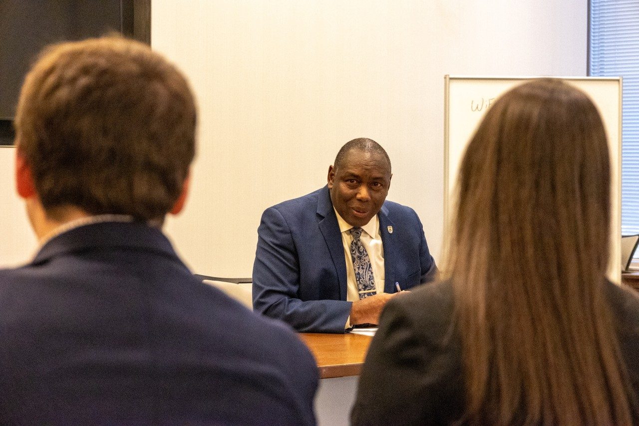 Man in a suit chats with students.