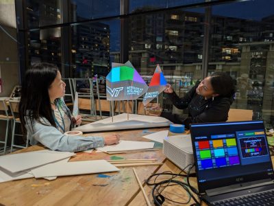 Two women projection-map onto suspended geometric forms in the Expressions Lab at Amazon HQ2 during the workshop “Projection Mapping.” Photo by David Franusich for Virginia Tech.