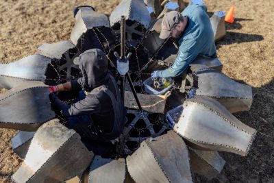 Rude Graves (at left) and Trevor Finney (at right) work inside the partially assembled base of Emergence, aligning structural hardware and preparing internal bracing. Photo by Damon Brewer for Virginia Tech.