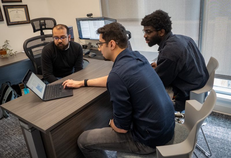 three computer scientists talk around laptop