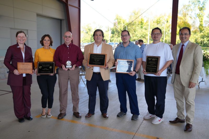 A group of  seven people, holding award plaques.