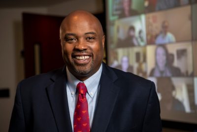 A person wearing a blazer, blue shirt, and tie with Virginia Tech on it