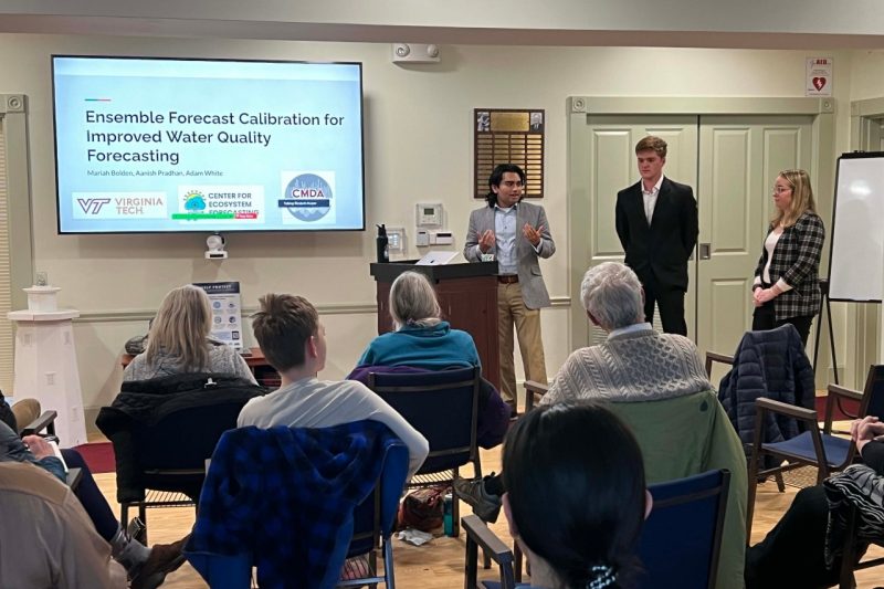 3 students give a presentation in a small room