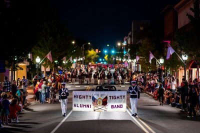 Image shows the Highty Tighty Alumni Band banner as it is carried down Main Street in downtown Blacksburg