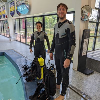 Two people in scuba gear at an indoor pool.