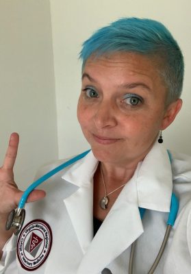 Veterinary student with blue hair and a blue stethoscope posing in a white lab coat.