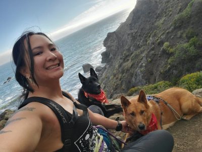 Denise Wrigley with her dogs at a cliff near the ocean.