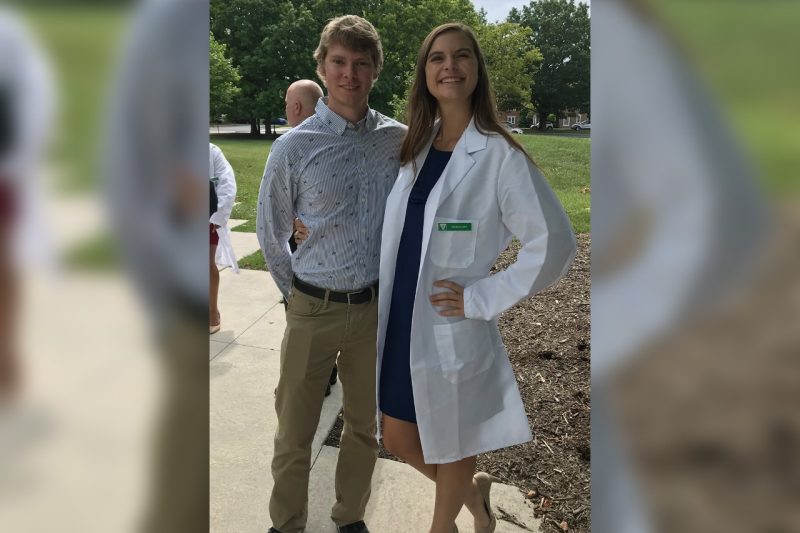 Cecelia Ivey (at right) in a white coat, standing with another person.