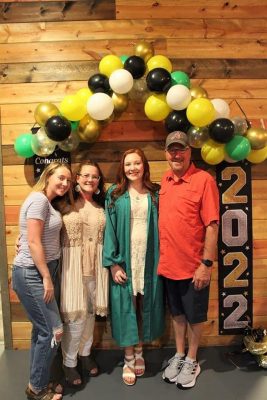 Karson Sluss in a graduation gown with her family. 