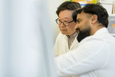 X.J. Meng (at left) working with members in his lab. Photo by Andrew Mann for Virginia Tech.