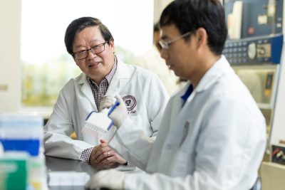 X.J. Meng (at left) working with members in his lab. Photo by Andrew Mann for Virginia Tech.