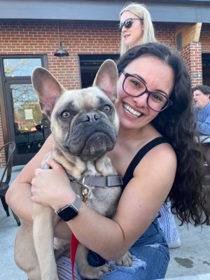 Lauren Maghak holding a French Bulldog sitting on an outdoor patio