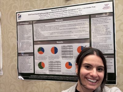 Lauren Maghak (at right) posing with a poster board of her research 