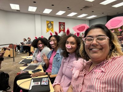 Marissa Vincent (at right) posing with a group of women. They are wearing pig ears and pig noses.