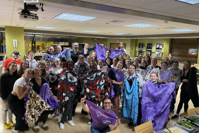 A group photo of public health and DVM students showing off blankets for purple leash week 