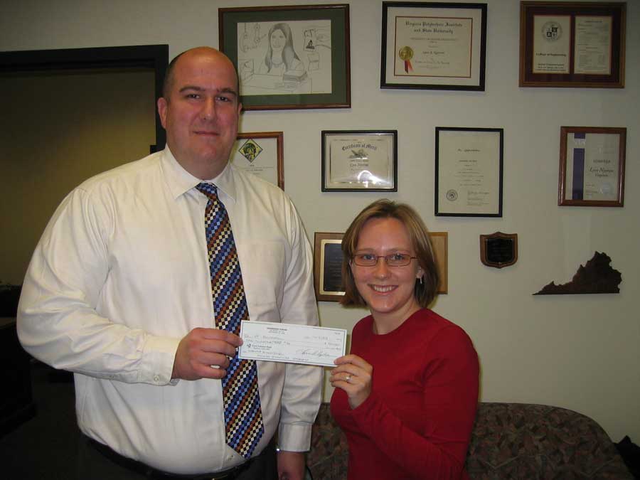 Kari Adkins (right), of Summerfield, N.C., the editor of the <em>Engineers' Forum</em>, the engineering college's student magazine, presents a $100,000 check to Erin Edwards, director of development for the College of Engineering at Virginia Tech.