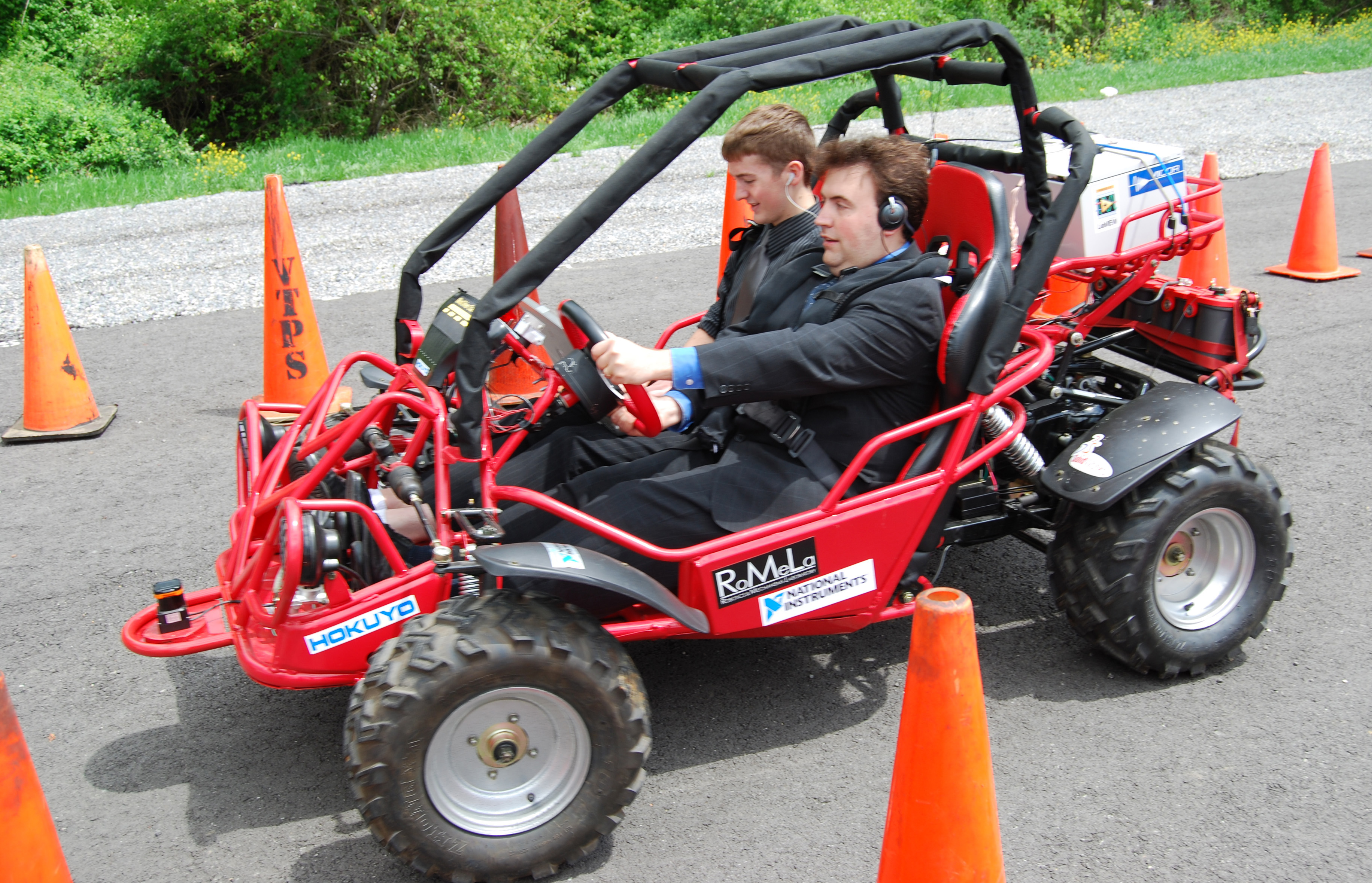 Mark Riccobono, executive director of the National Federation of the Blind's Jernigan Institute, drives the Virginia Tech Blind Driver Challenge vehicle through an obstacle course of traffic cones on a campus parking lot. In the passenger seat is Greg Jannaman, who led the student team within the mechanical engineering department during the past year, and is monitoring the software of the vehicle..