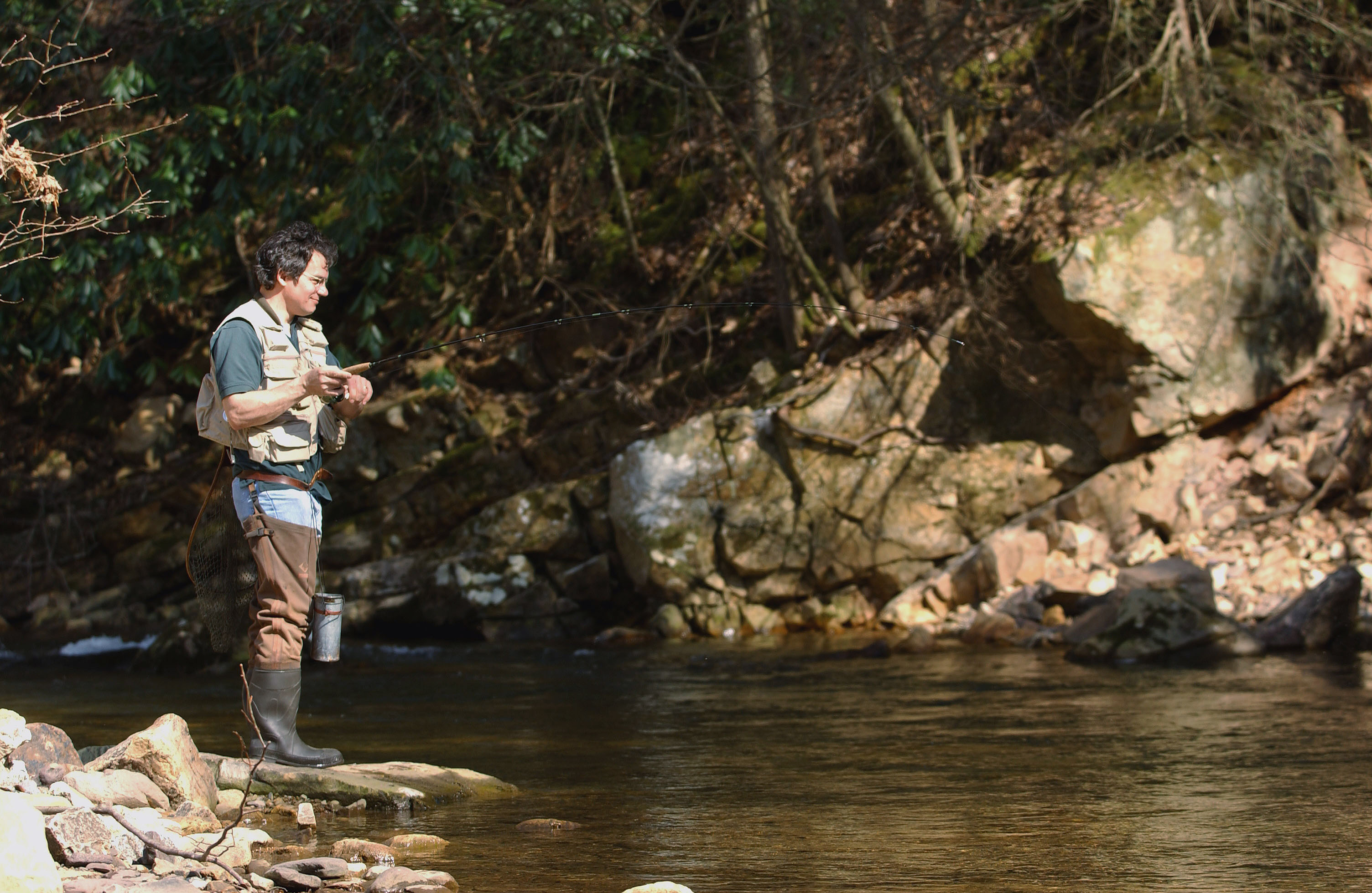 A fisherman in a forest creek