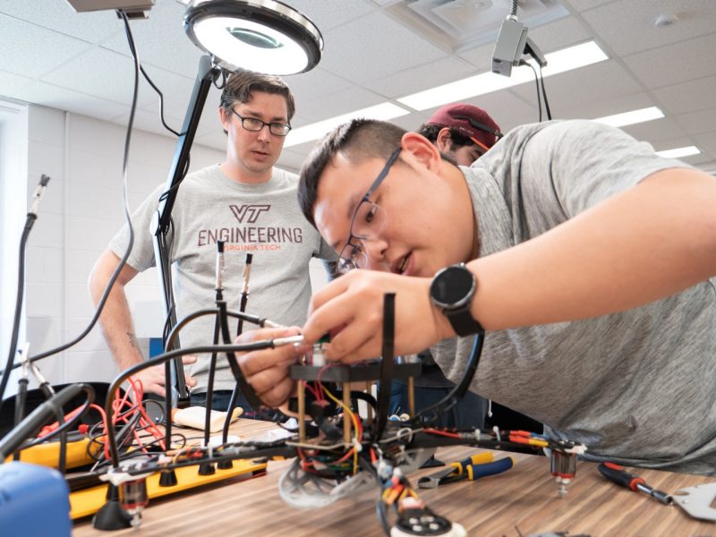 Ryan Ard ’22, mechanical engineering (left) watches Yuezhong Xu ’22, electrical and computer engineering (right) connect electrical components of their drone. Photo by Chase Parker for Virginia Tech.