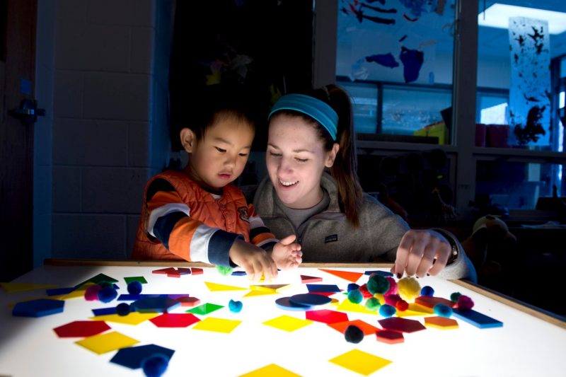 child and teacher working at a table