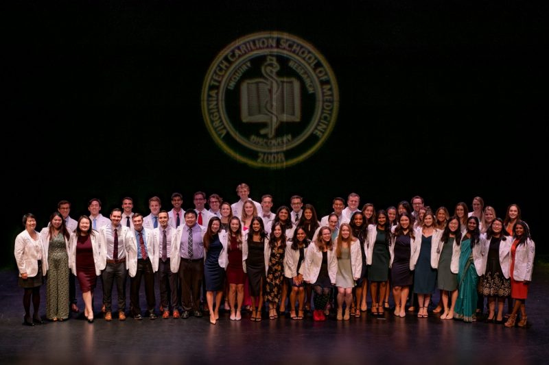Students from the VTCSOM Class of 2026 gather on stage after receiving their white coats.