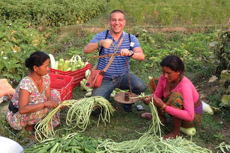 Two women flank Virginia Tech scientist as they weigh long beans