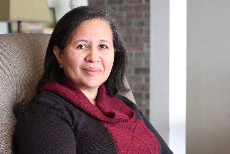 A photo of Maria De Los Angeles Adames seated in a chair in a living room. 