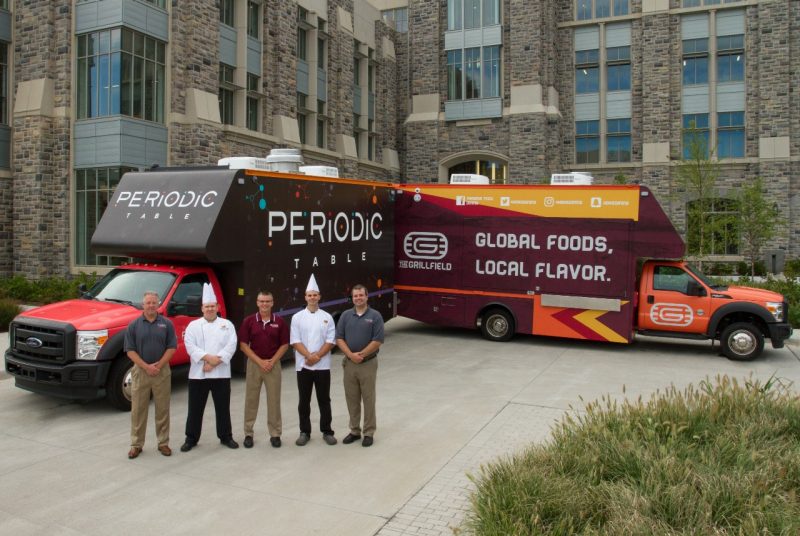 Bill Hess, Randy Van Dyke, Ted Faulkner, Robert Obst, and Gabe Petry pose infront of the two food trucks. 