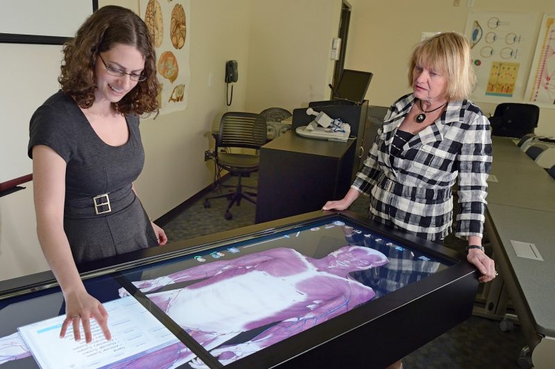Dean Cynda Johnson, along with an unnamed student, studies a computer model of the human body.