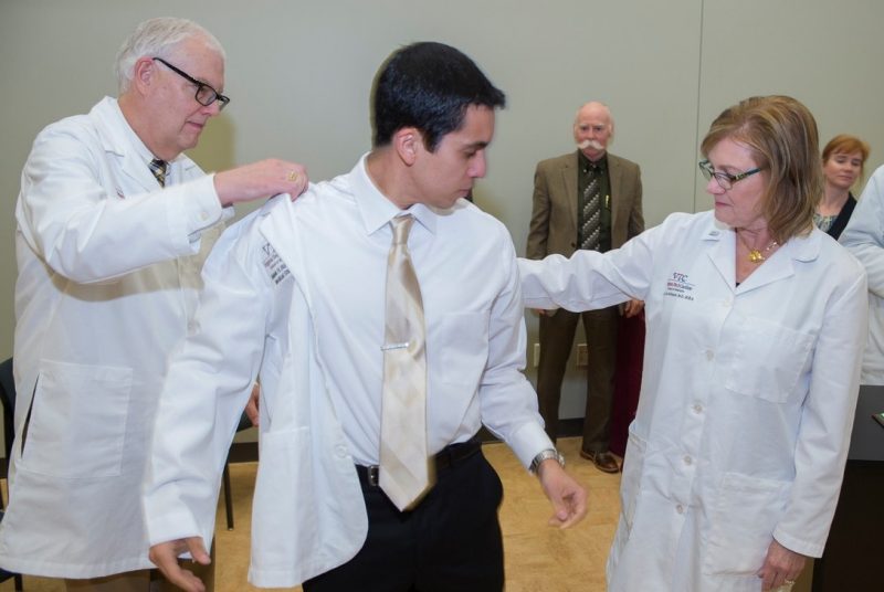 student helped into his white coat