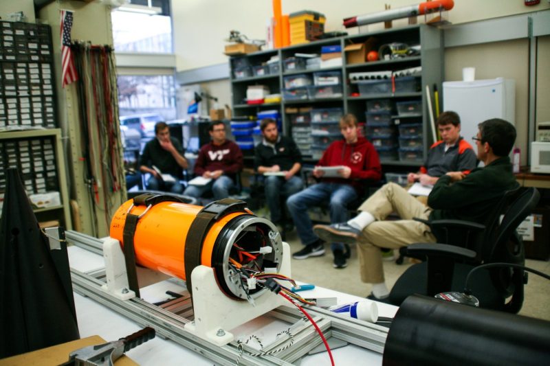 A photo of the bright orange 690 AUV, with the Virginia DEEP-X team in the background.