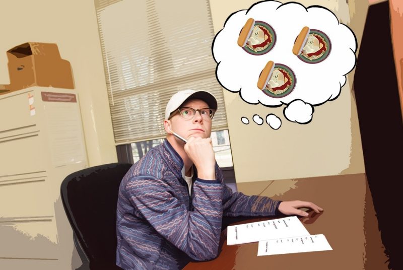 Michael Hanson sits at a desk, taking a test. A cartoon thought bubble is above him with graphics of chicken parmesan.