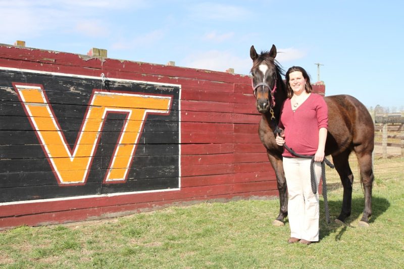 Joanna Kania poses with horse in front of VIrginia Tech sign