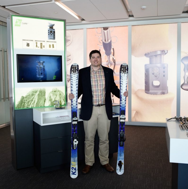 Clint Boyd is pictured with a display of the medical device he developed for K2M  and a pair of  custom skis, designed with spines, that he made for K2M's chief executive officer.