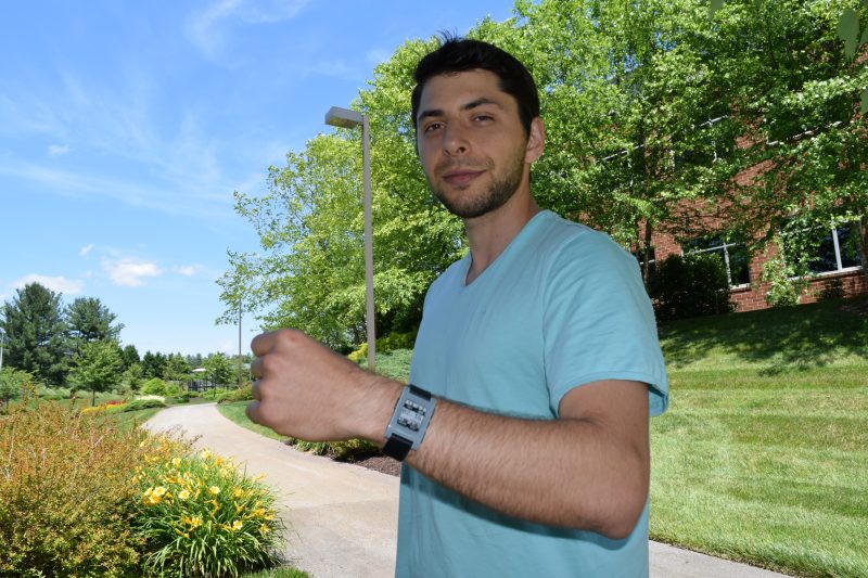 A young man holds up his wrist to reveal the smartwatch he developed.