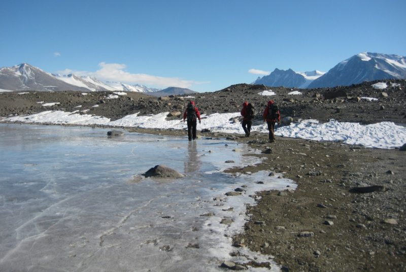 Researchers walk alongside Spalding Pond in Taylor Valley, Antarctica