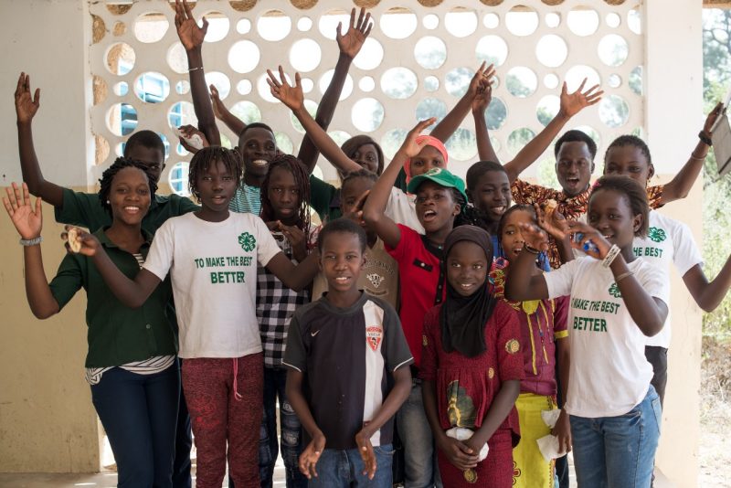 A group of middle school aged children in Senegal waving.