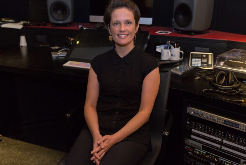 Woman sits in chair posing for photo at radio studio