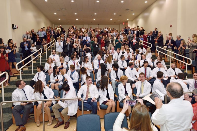 Crowd claps for class during white coat ceremony