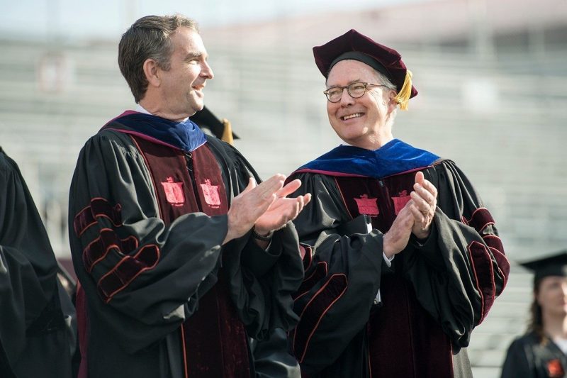 Historic Day Two men wearing commencement regalia smile and clap.