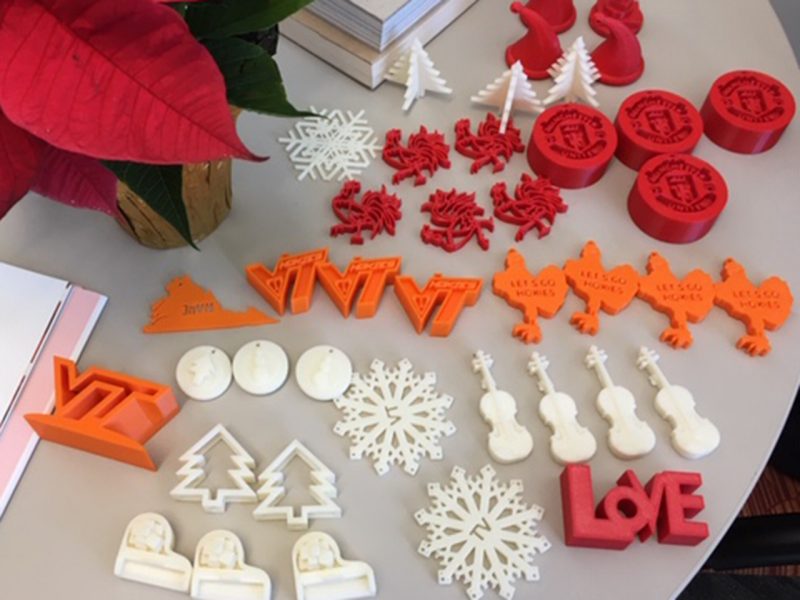 Examples of the 3D-printed ornaments students shared with residents of the Wybe and Marietje Kroontje Health Care Center at Warm Hearth Village. Ornament shapes include orange VT logos and Hokie Birds, white trees and snowflakes, and red roosters and toboggan hats.