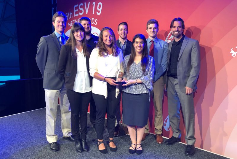 Seven students and their professor hold a glass trophy they received as the winners of the international 2019 Collegiate Student Safety Technology Design Competition. 