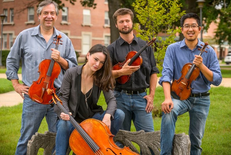The Ceruti String Quartet poses for an outdoor photo with their instruments.