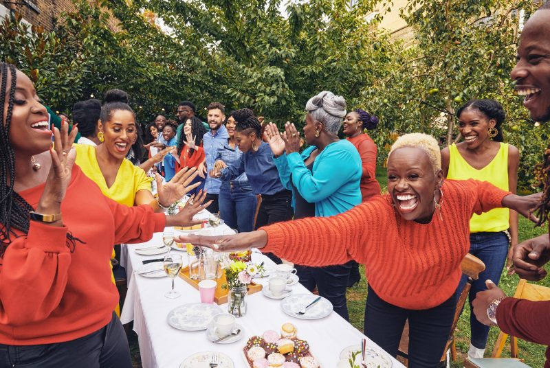 Members of gospel ensemble The Kingdom Choir joyfully celebrate around a dinner table.