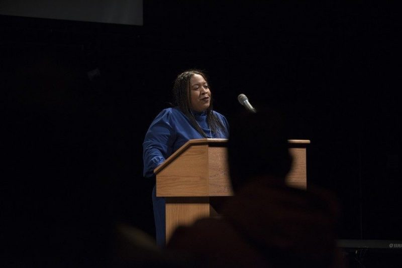 Brandy Faulkner speaking at a podium in a dark blue robe 