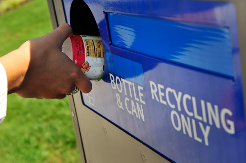 Image of a student recycling a bottle into a recycling container on campus